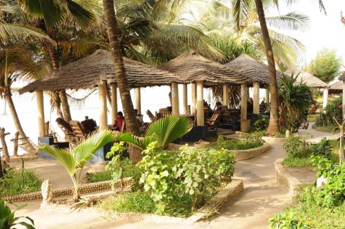 a restaurant with chairs and palm trees on the beach at Leybato Beach Hotel in Fajara
