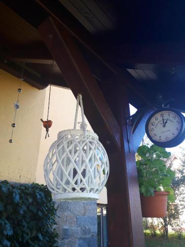 a white bird cage hanging from a building with a clock at Penzion Romance in Vyšší Brod
