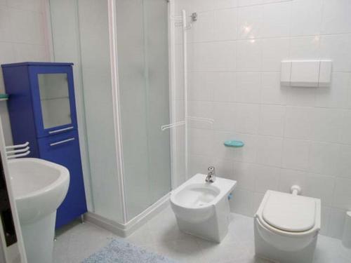 a white bathroom with a toilet and a sink at Villa Eleonora in Grado