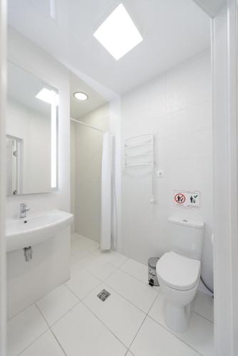 a white bathroom with a toilet and a sink at Partner Guest House Baseina in Kyiv
