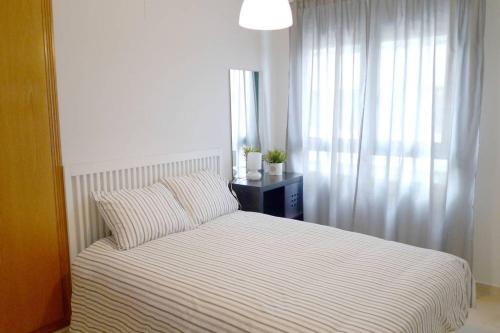 a bedroom with a bed with a striped bedspread and a window at Apartamento en la Ciudad de las ciencias in Valencia