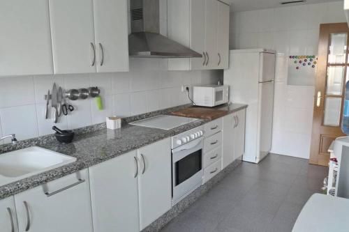 a kitchen with white cabinets and a stove top oven at Apartamento en la Ciudad de las ciencias in Valencia