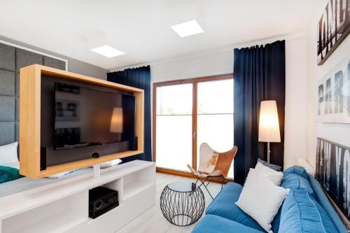a living room with a blue couch and a tv at Bed&Bath Luxury Apartments in Krakow