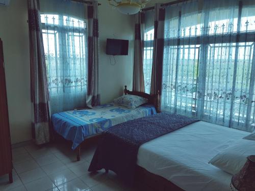 two twin beds in a room with windows at Luxor Residence Guesthouse in Belle Mare