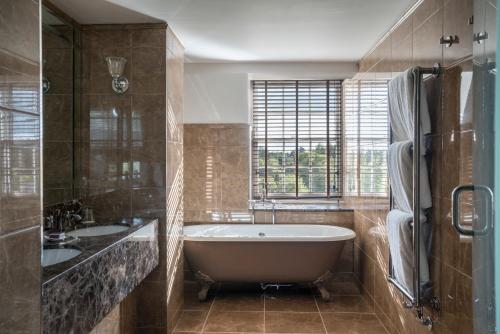 a bathroom with a tub and two sinks and a window at The Gleneagles Hotel in Auchterarder