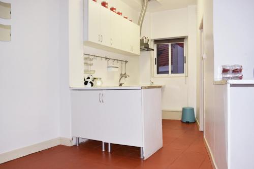 eine Küche mit weißen Schränken und roten Fliesenböden in der Unterkunft Bairro Alto Central Apartment Lisbon in Lissabon