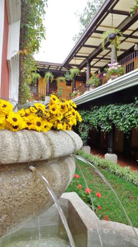 a fountain with yellow flowers in front of a building at Hotel Meson del Valle by AHS in Antigua Guatemala