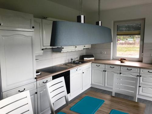 a kitchen with white cabinets and a blue hood at Haus "Kliffruhe" in Glowe