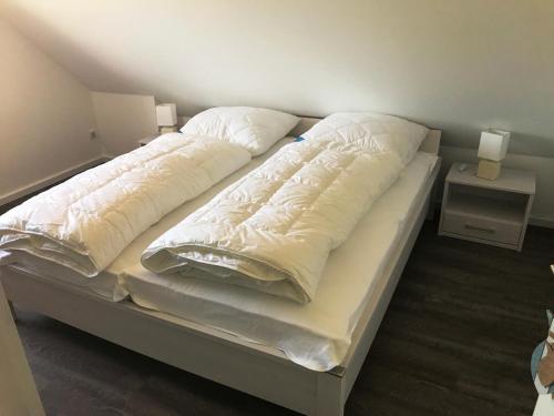 ein großes Bett mit weißer Bettwäsche und Kissen in der Unterkunft Haus "Kliffruhe" in Glowe