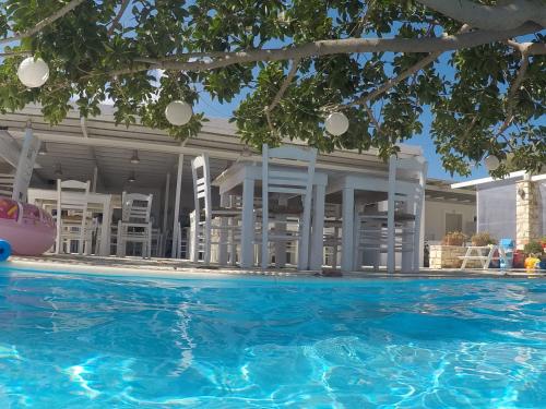 a swimming pool in front of a building with white chairs at Margarita Studios Ambelas in Ambelas