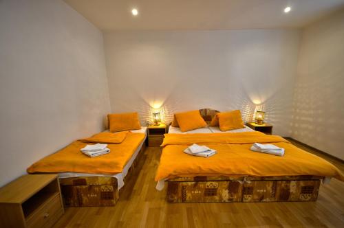 イェセニークにあるApartman Nad Laznemiのオレンジのシーツが備わる客室内のベッド2台