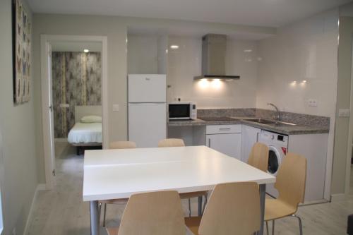 cocina blanca con mesa blanca y sillas en Apartamentos Logroño Centro en Logroño