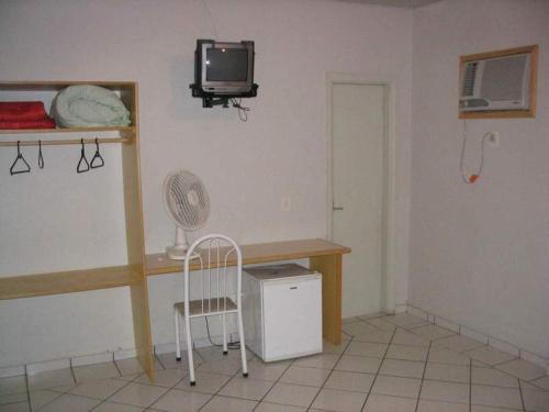 a room with a desk and a tv and a chair at Hotel Topazio Ltda in Umuarama