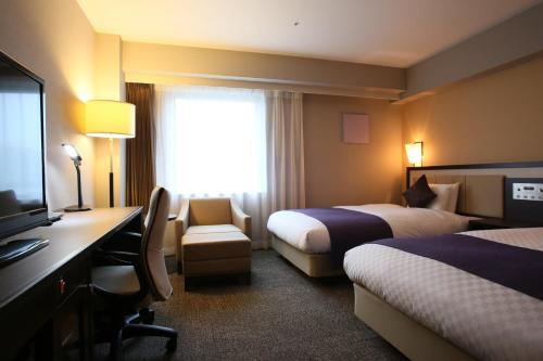 um quarto de hotel com duas camas e uma secretária e uma televisão em Daiwa Roynet Utsunomiya em Utsunomiya