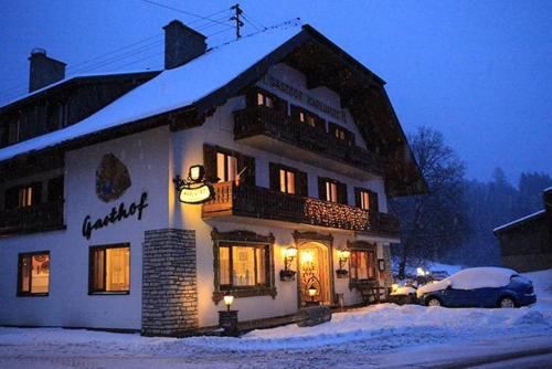 a snow covered house with a car parked in front of it at Gasthof Karlwirt in Sankt Andrä im Lungau