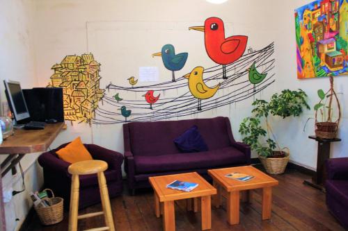 a living room with a couch and birds painted on the wall at Casa Volante Hostal in Valparaíso