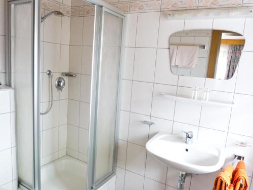 a white bathroom with a shower and a sink at Haus Dorfplatz in Galtür
