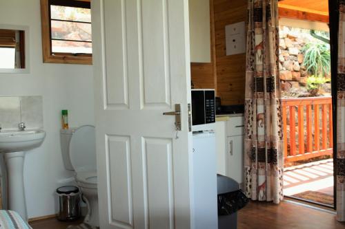 baño con aseo y puerta que conduce a un porche en Lerato Bush Lodge, en Pretoria
