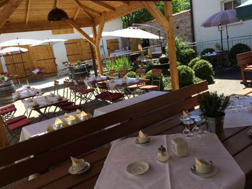 restauracja z białymi stołami, krzesłami i parasolami w obiekcie Landgasthof & Landhotel Wild w mieście Haunwang