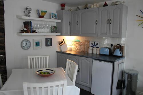 a kitchen with white cabinets and a table and chairs at Cara-Na-Mara in Killough