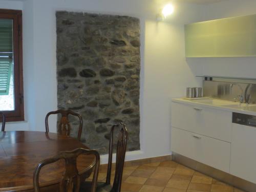 cocina con mesa y pared de piedra en Vista Alpi Apuane, en Rometta