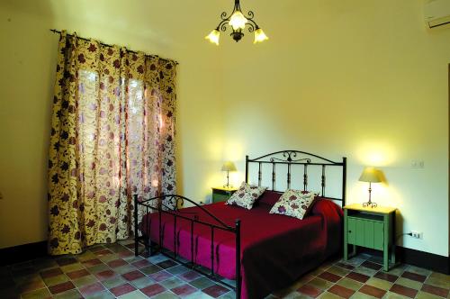 a bedroom with a red bed with two tables and a window at Antica Dimora Benanti in Milo
