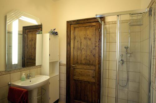 a bathroom with a sink and a shower with a wooden door at Antica Dimora Benanti in Milo