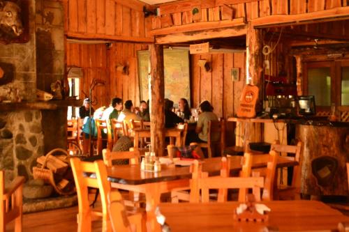 um grupo de pessoas sentadas em um restaurante com mesas e cadeiras em Hosteria-Cabañas Rucapillan em Choshuenco