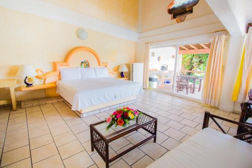 um quarto com uma cama e uma mesa com flores em Hotel Casa Sun and Moon em Zihuatanejo