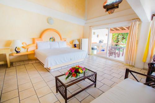 a bedroom with a bed and a table with flowers on it at Hotel Casa Sun and Moon in Zihuatanejo