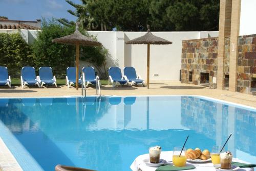 una piscina con sillas y una mesa con bebidas en Hotel Marisma Sancti Petri, en Chiclana de la Frontera