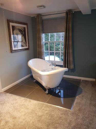 uma banheira branca na casa de banho com uma janela em The Coach Hotel em Coleshill