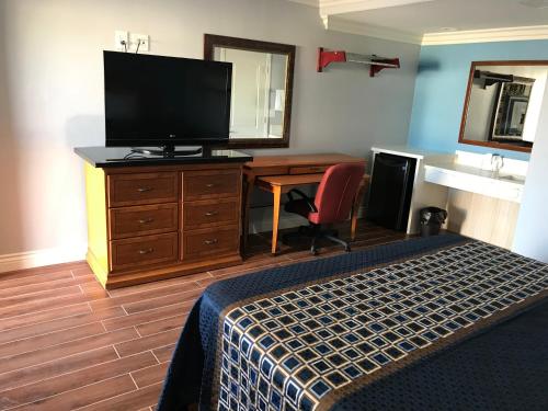 a bedroom with a bed and a desk with a television at Driftwood Motel in Torrance
