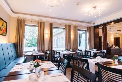 a restaurant with tables and chairs and windows at HOTEL KOCKS am Mühlenberg in Mülheim an der Ruhr