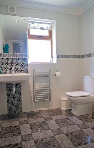 a bathroom with a toilet and a sink and a window at Jonti Bed And Breakfast in Corfe Castle