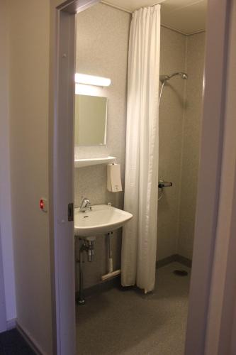 a bathroom with a sink and a shower with a mirror at Vildbjerg Sports Hotel & Kulturcenter in Vildbjerg