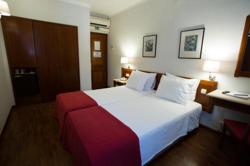 a hotel room with a large bed and a desk at Hotel Solaris in Setúbal
