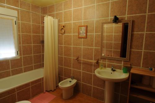 een badkamer met een wastafel, een toilet en een spiegel bij El Taller in San Bartolomé de Tormes