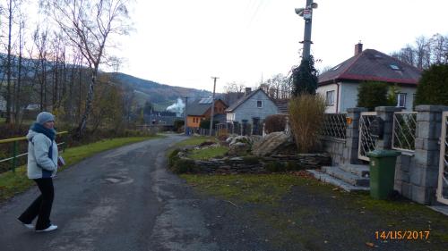 a woman walking down a road near a house at Apartman U Hanicky in Bělá pod Pradědem
