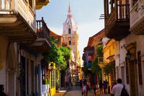a group of people walking down a street with a clock tower at Hotel Boutique Casa Córdoba Estrella in Cartagena de Indias