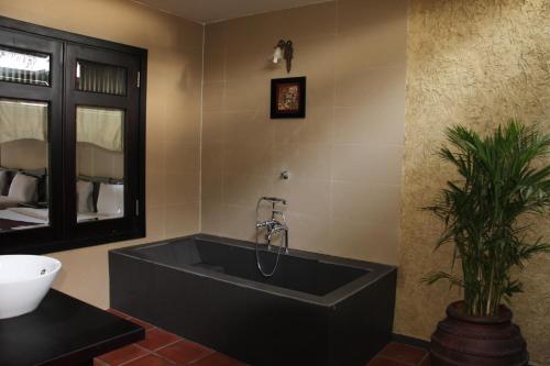 baño con bañera negra grande y planta en Lotus Village Resort, en Mui Ne