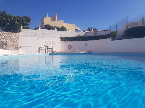 een zwembad met blauw water voor een wit gebouw bij Casa da Ana in Carvoeiro