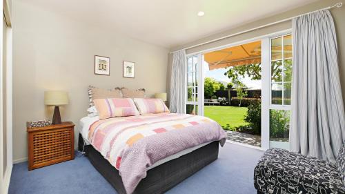 a bedroom with a bed and a large window at Olive House Bed and Breakfast in Christchurch