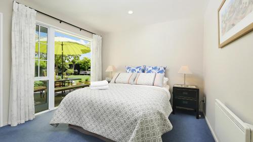a bedroom with a bed and a window with an umbrella at Olive House Bed and Breakfast in Christchurch