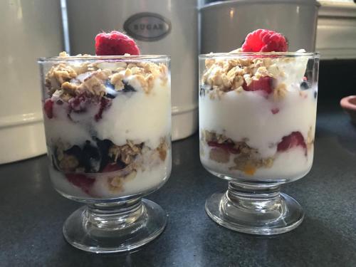 威廉斯堡威廉斯堡白宫酒店 的柜台上放着两杯盛有浆果和坚果的甜点。