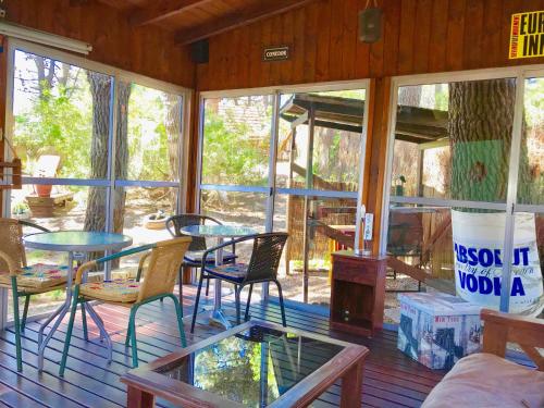 a screened in porch with tables and chairs and windows at B&B Mi Casa Es Tu Casa in Mar Azul