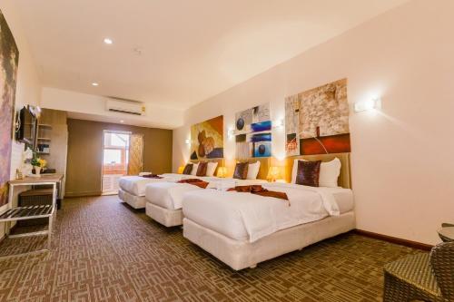 a row of four beds in a hotel room at Roseate Chiang Mai in Chiang Mai