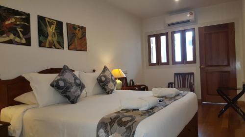 a bedroom with a bed with white sheets and pillows at Heeren Straits Hotel in Melaka
