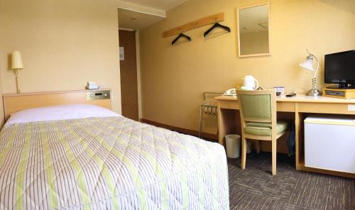a hotel room with a bed and a desk with a computer at Hotel Koga Hills (Former: Koga Ark Hotel) in Koga