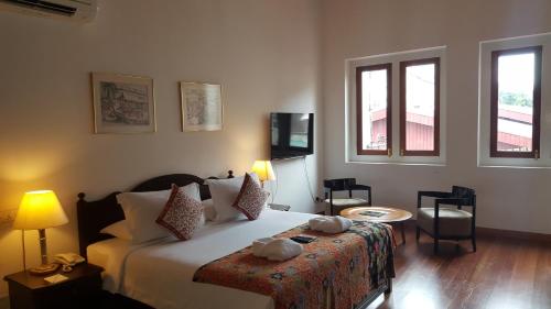 a bedroom with a bed and two windows at Heeren Straits Hotel in Melaka
